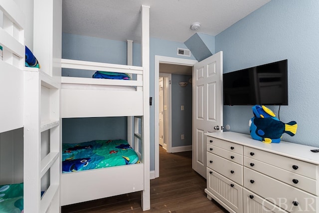 bedroom featuring baseboards, a textured ceiling, visible vents, and dark wood-type flooring