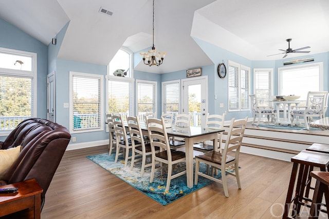 dining area with lofted ceiling, visible vents, wood finished floors, baseboards, and ceiling fan with notable chandelier