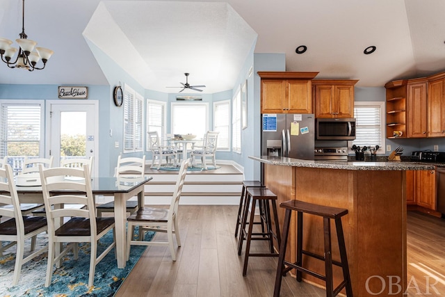 kitchen with stainless steel appliances, pendant lighting, light wood-style flooring, and open shelves