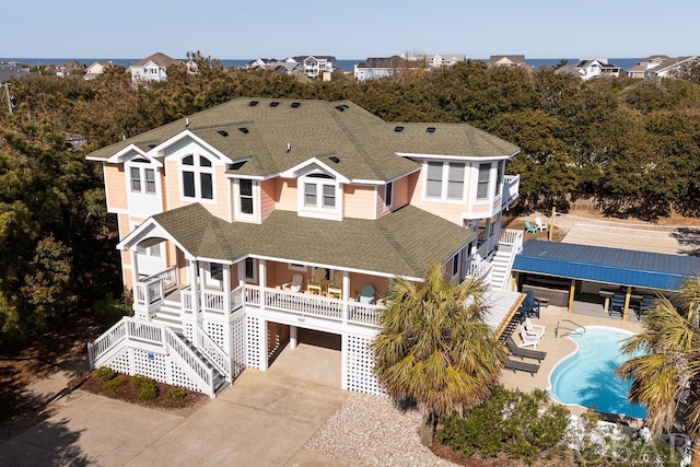 view of front facade with roof with shingles, stairway, a patio area, and an outdoor pool