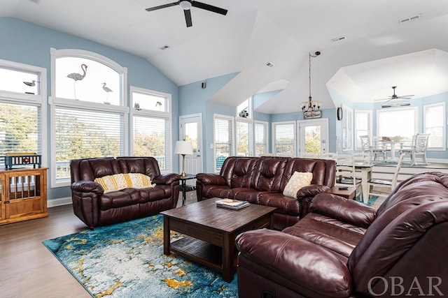 living room featuring ceiling fan with notable chandelier, lofted ceiling, visible vents, and wood finished floors