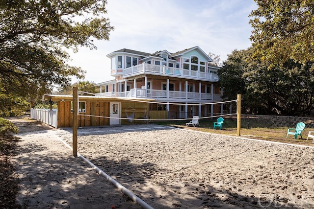 exterior space featuring a balcony, fence, and volleyball court