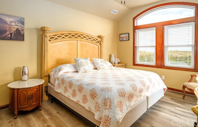 bedroom with visible vents, vaulted ceiling, baseboards, and wood finished floors