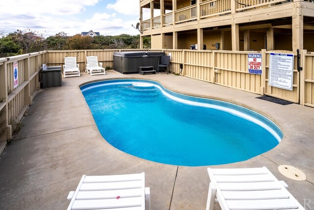 view of swimming pool with a hot tub, fence, and a fenced in pool