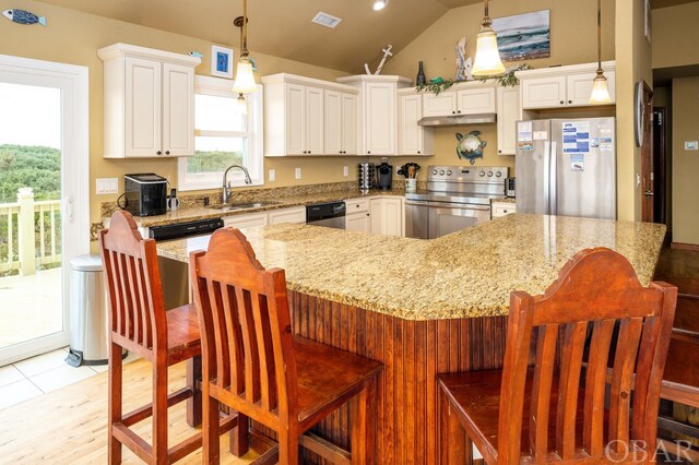 kitchen with appliances with stainless steel finishes, a sink, decorative light fixtures, and a kitchen breakfast bar