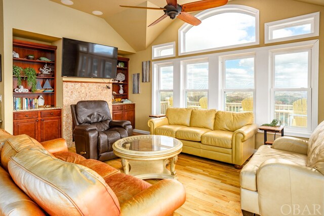 living room with light wood finished floors, ceiling fan, and vaulted ceiling