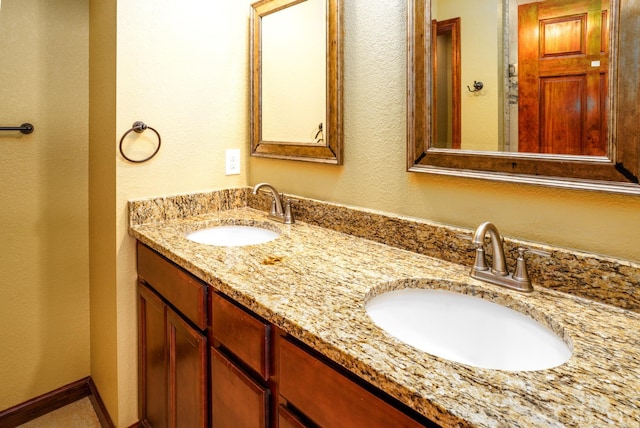 full bathroom featuring a sink, baseboards, and double vanity