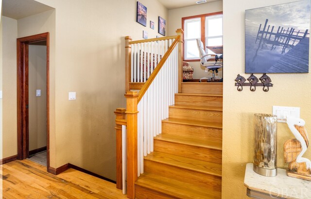 stairway featuring wood finished floors, visible vents, and baseboards