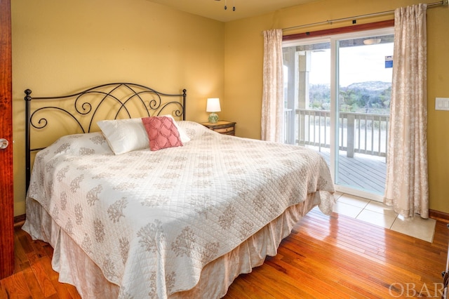 bedroom with access to exterior and wood finished floors