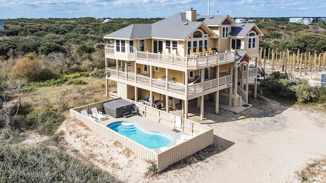 back of house with a patio, a balcony, roof with shingles, a fenced in pool, and a hot tub