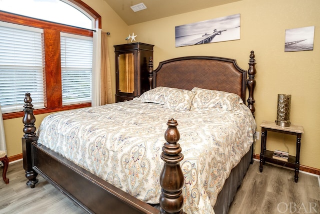 bedroom featuring lofted ceiling, wood finished floors, visible vents, and baseboards