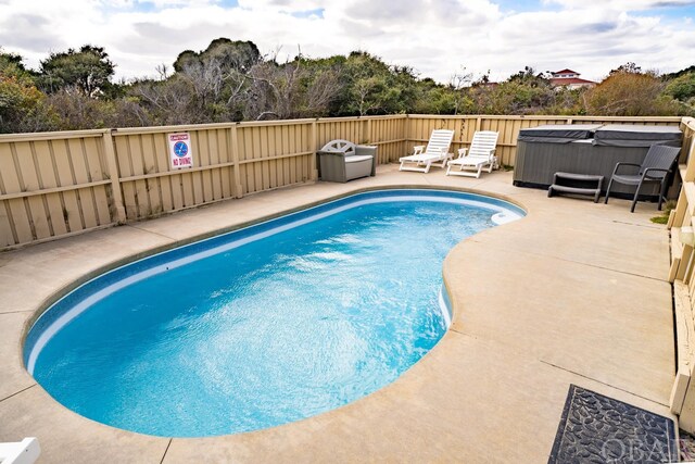 view of swimming pool with a fenced in pool, a patio area, and a hot tub