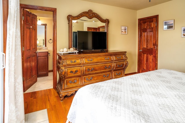 bedroom featuring ensuite bath and light wood-style flooring