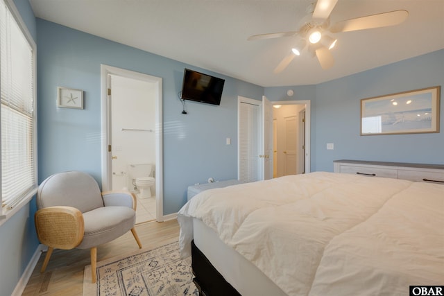 bedroom with ensuite bathroom, ceiling fan, light wood-type flooring, and baseboards