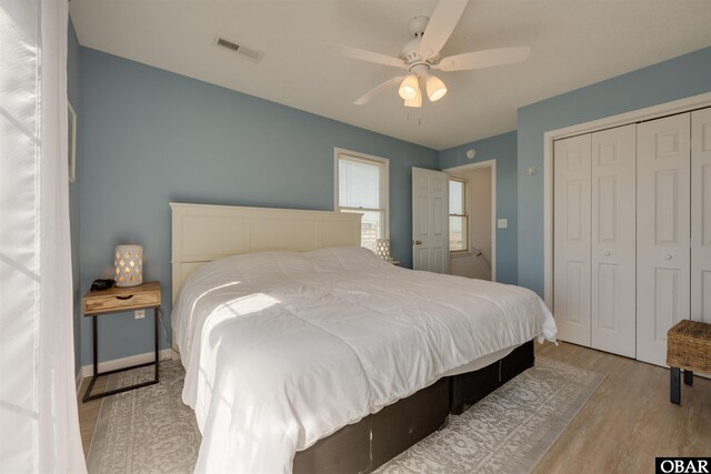 bedroom featuring baseboards, visible vents, a ceiling fan, wood finished floors, and a closet