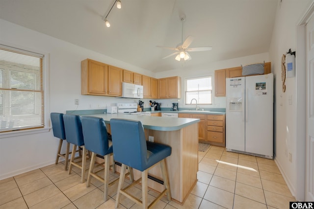 kitchen featuring light countertops, light tile patterned flooring, a sink, white appliances, and a peninsula