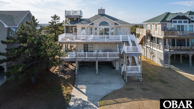 rear view of house with driveway, a carport, and a balcony