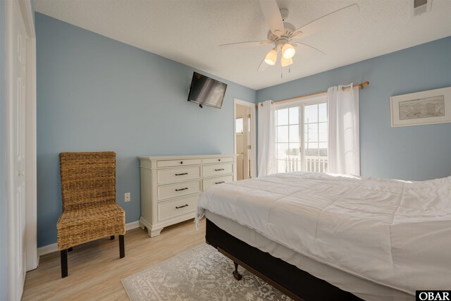 bedroom featuring ceiling fan, light wood-style flooring, visible vents, and baseboards