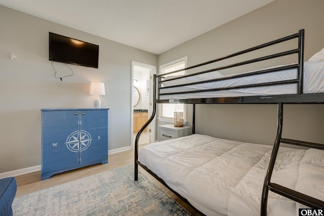 bedroom with baseboards, wood finished floors, and ensuite bathroom