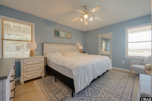 bedroom with light wood finished floors, baseboards, and a ceiling fan