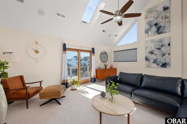 carpeted living room featuring a skylight, a ceiling fan, visible vents, and high vaulted ceiling