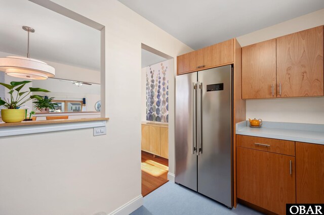 kitchen with baseboards, pendant lighting, light countertops, and high end fridge