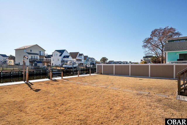 view of yard featuring a water view, fence, and a residential view