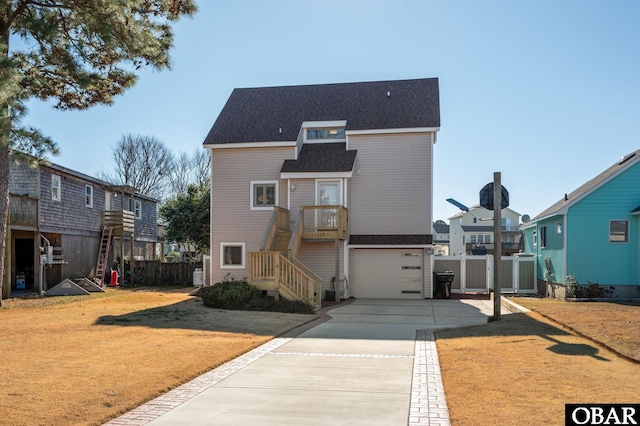 view of front of house with a front yard, concrete driveway, fence, and a residential view