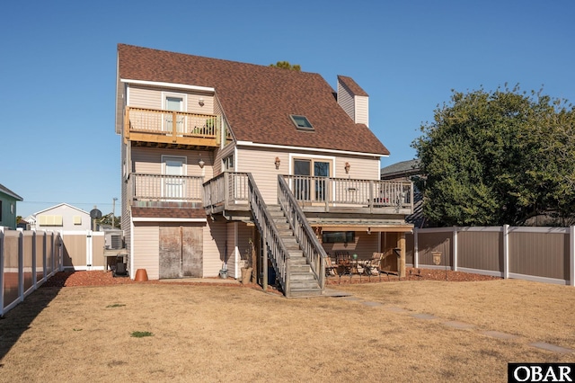 rear view of house featuring a chimney, a shingled roof, stairway, a deck, and a fenced backyard