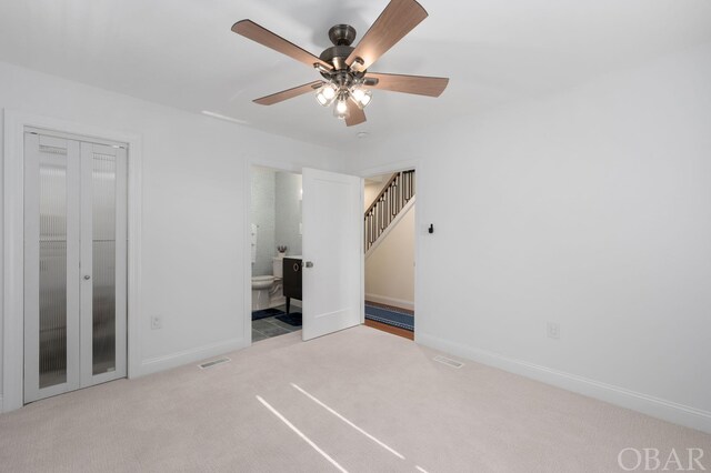 unfurnished bedroom featuring visible vents, light carpet, ceiling fan, ensuite bath, and baseboards