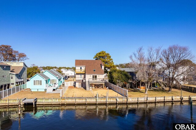 rear view of property with a residential view, a fenced backyard, a water view, and stairs