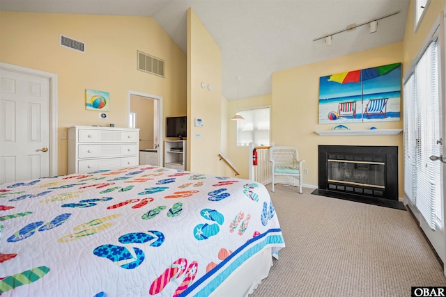 bedroom with a fireplace with flush hearth, track lighting, visible vents, and carpet flooring