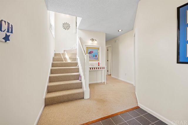 stairway with carpet, a textured ceiling, and baseboards