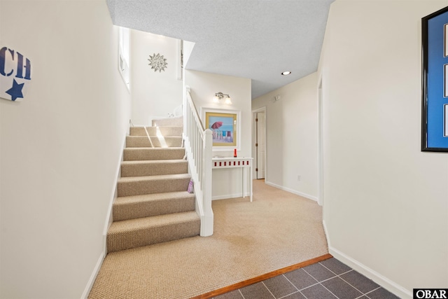 staircase with baseboards, carpet flooring, tile patterned flooring, and a textured ceiling