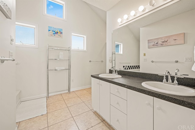 full bathroom with vaulted ceiling, double vanity, a sink, and tile patterned floors