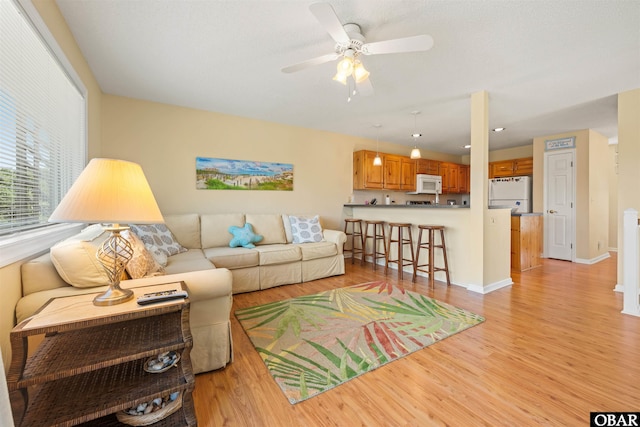 living room with baseboards, light wood-style floors, and ceiling fan