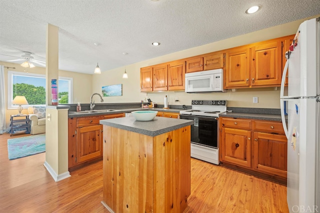 kitchen with white appliances, dark countertops, a center island, a peninsula, and a sink