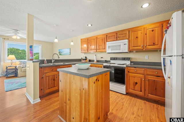 kitchen with dark countertops, a sink, a textured ceiling, white appliances, and a peninsula