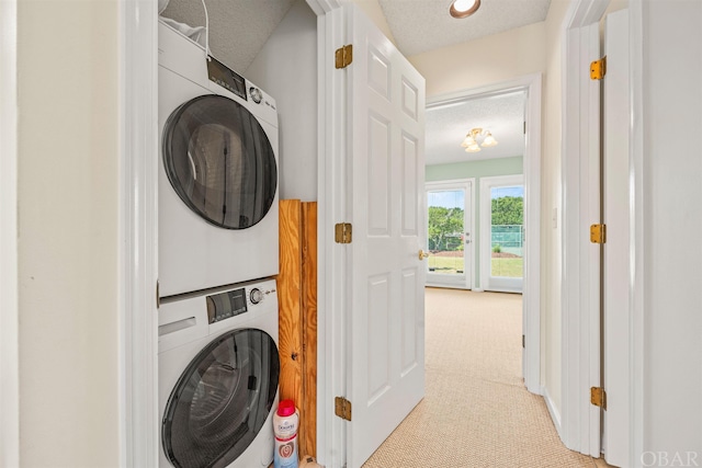 clothes washing area with stacked washer and clothes dryer, light carpet, a textured ceiling, and laundry area