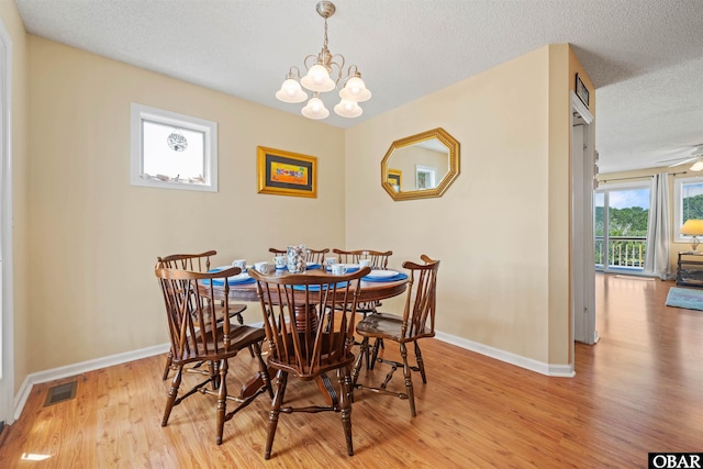 dining area featuring baseboards, visible vents, light wood-style flooring, an inviting chandelier, and a textured ceiling