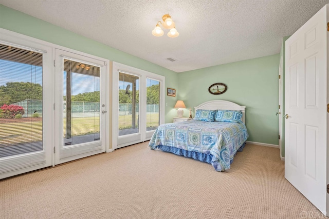 bedroom with access to outside, visible vents, a textured ceiling, and carpet