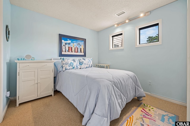 bedroom featuring visible vents, light carpet, a textured ceiling, and baseboards