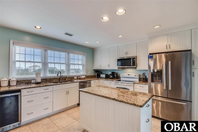 kitchen featuring visible vents, wine cooler, appliances with stainless steel finishes, stone counters, and a sink