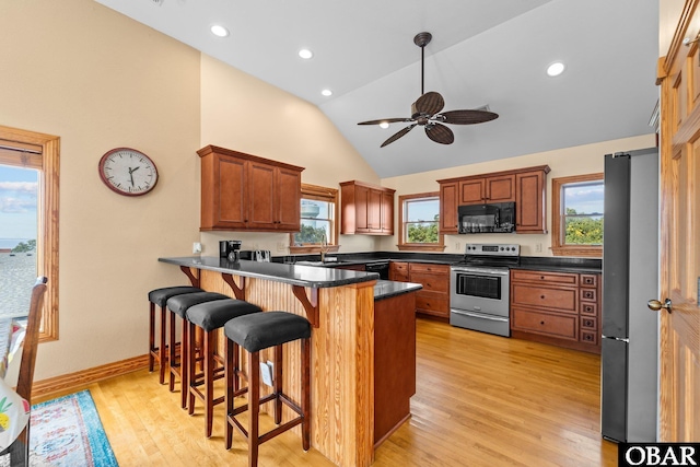 109 Duck Ridge Village Ct Lot 14, Duck, NC 27949 - kitchen with stainless steel appliances, a peninsula, a kitchen bar, light wood-style flooring, and high vaulted ceiling