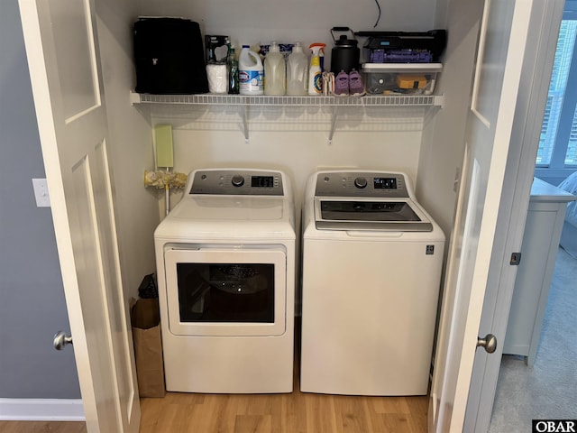 clothes washing area featuring light wood-type flooring and washer and clothes dryer