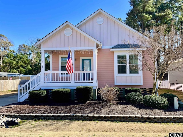 bungalow-style home with board and batten siding, stairway, a porch, and fence