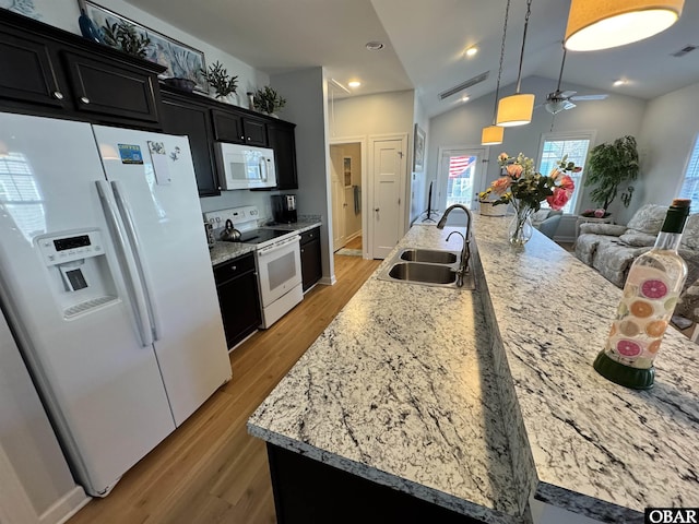 kitchen with dark cabinetry, a sink, white appliances, open floor plan, and ceiling fan