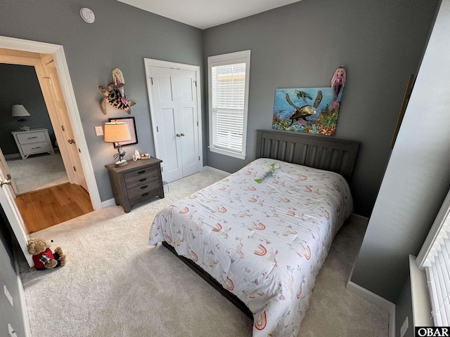 bedroom with light carpet, baseboards, and a closet