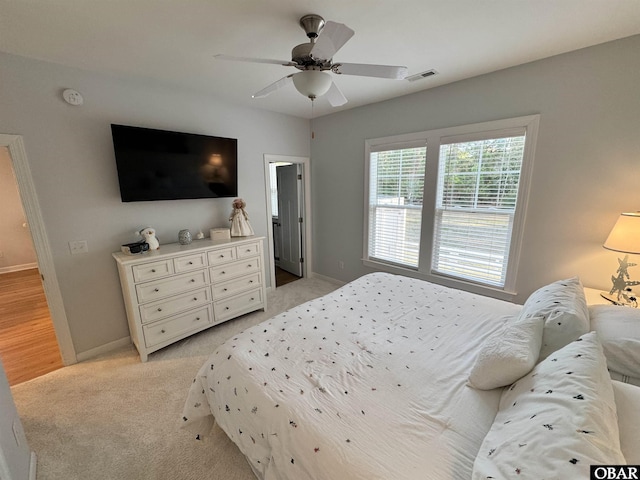 bedroom with visible vents, a ceiling fan, light colored carpet, and baseboards