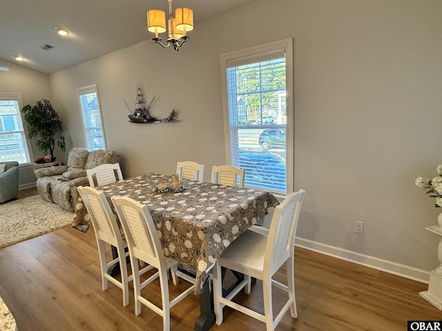 dining space with baseboards, a chandelier, wood finished floors, and visible vents
